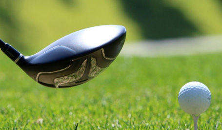 Golfschläger und ein Golfball auf einer hellgrünen Rasen