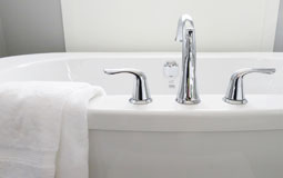 Kleine Grafik zum Thema Badewanne mit einer weißen Badewanne über die ein weißes Handtuch hängt