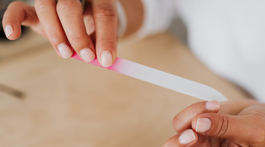 Grafik zum Thema Maniküre mit Frauenhänden, die mit einer Nagelfeile die eigenen Fingernägel pflegen