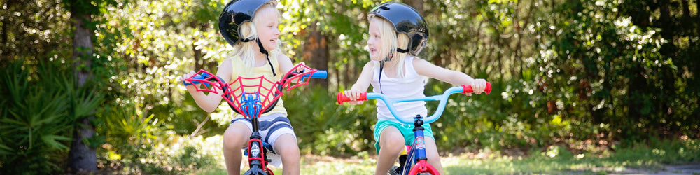 Zwei kleine Kinder mit schwarzen Helmen auf Kinderfahrrädern
