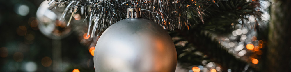 Silberne Christbaumkugel hängt an einem Weihnachtsbaum